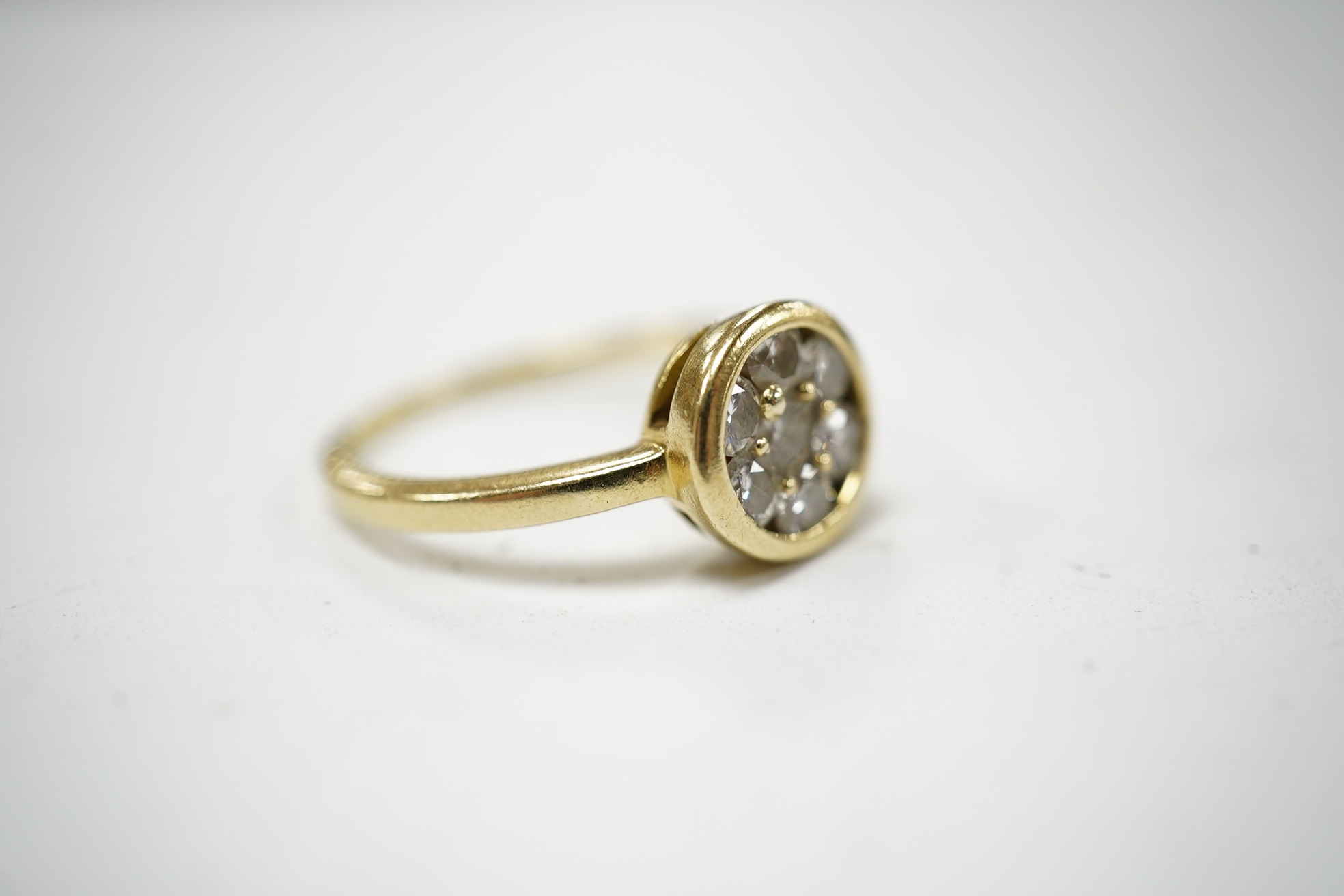 A yellow metal and seven stone diamond cluster set circular ring, size N/O, gross weight 3.4 grams. Condition - fair to good
